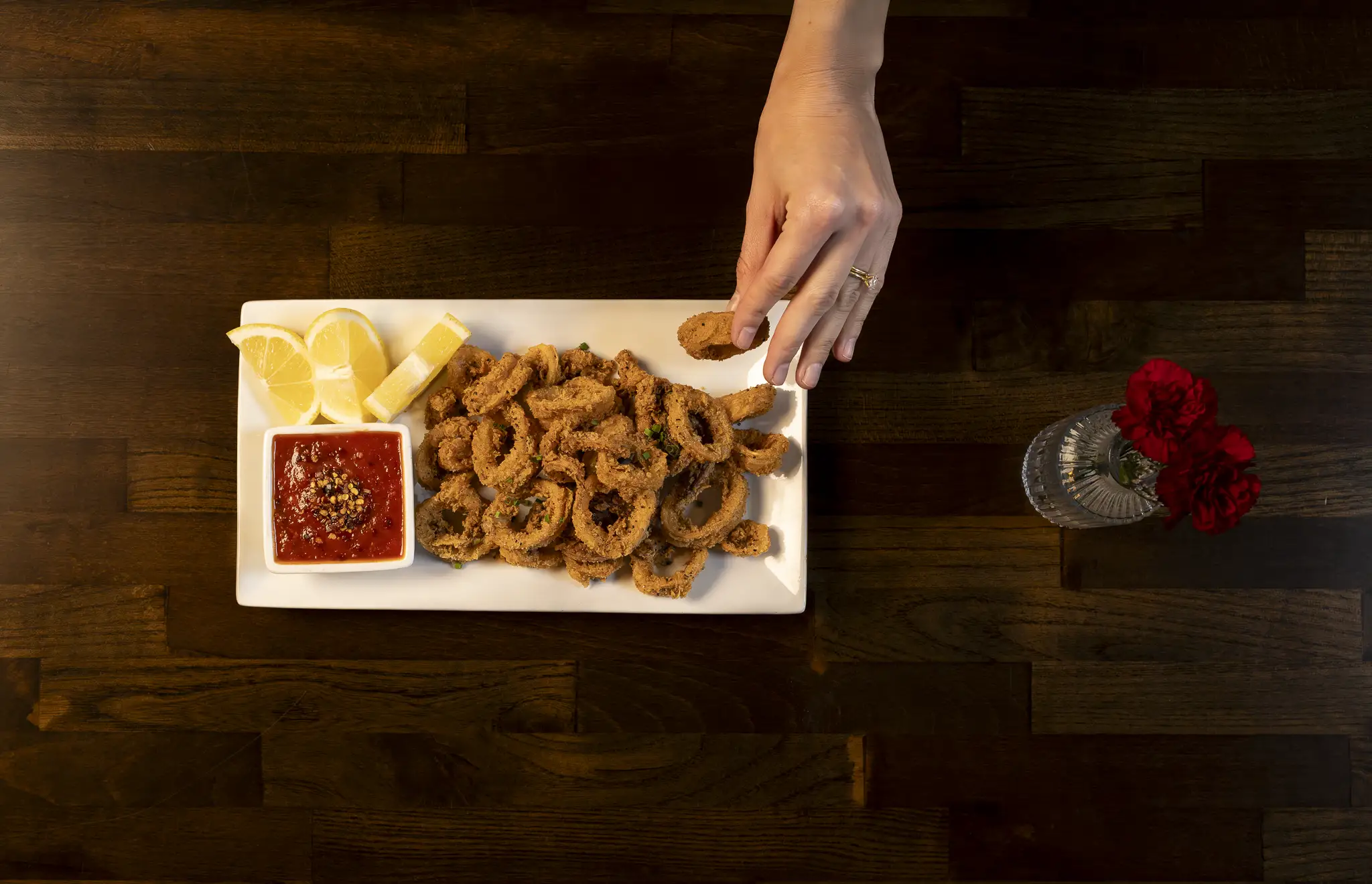 Overhead view of fried calamari with marinara sauce and lemon wedges