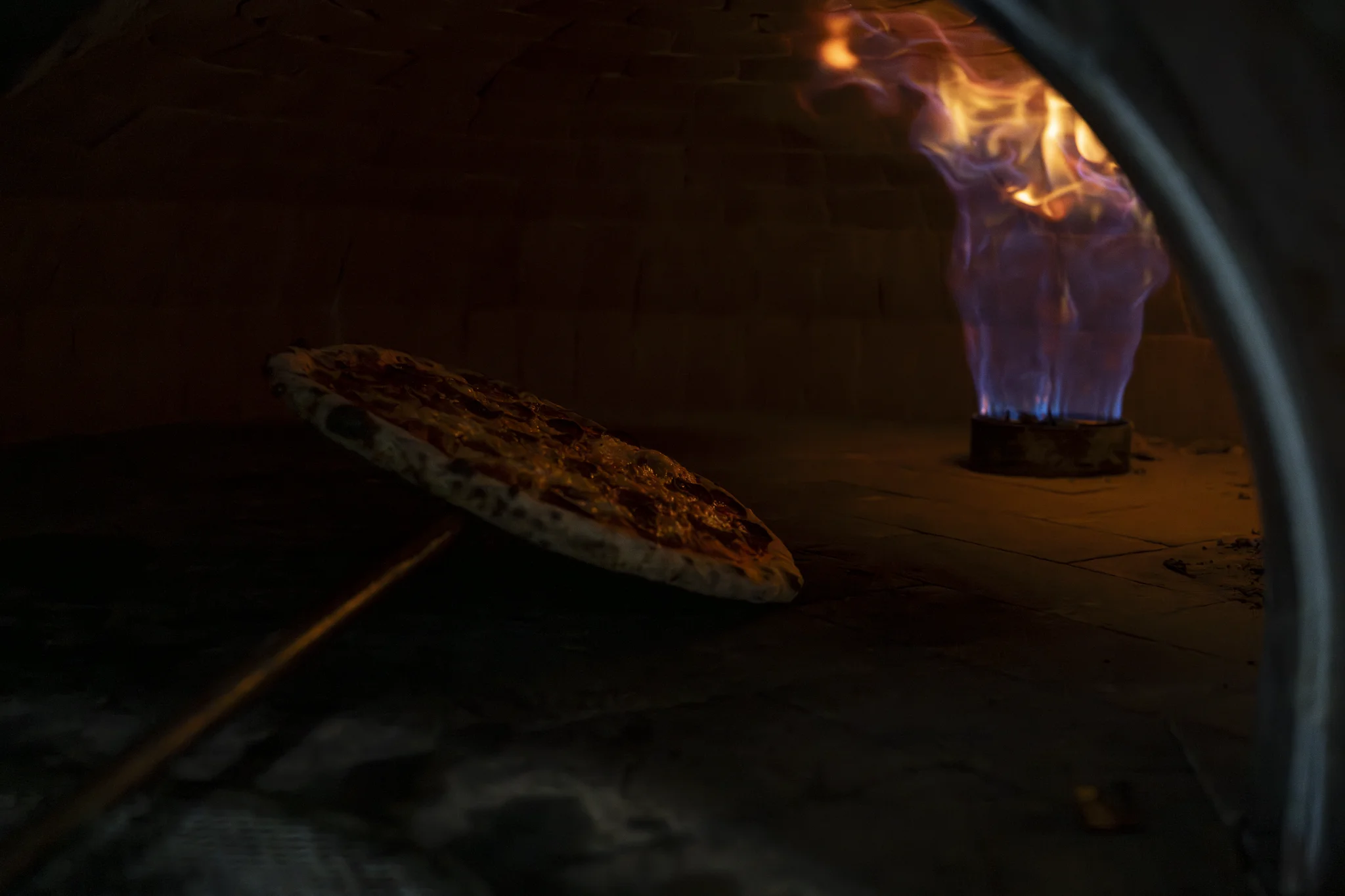 Neapolitan pizza cooking inside the wood-fired oven with open flames