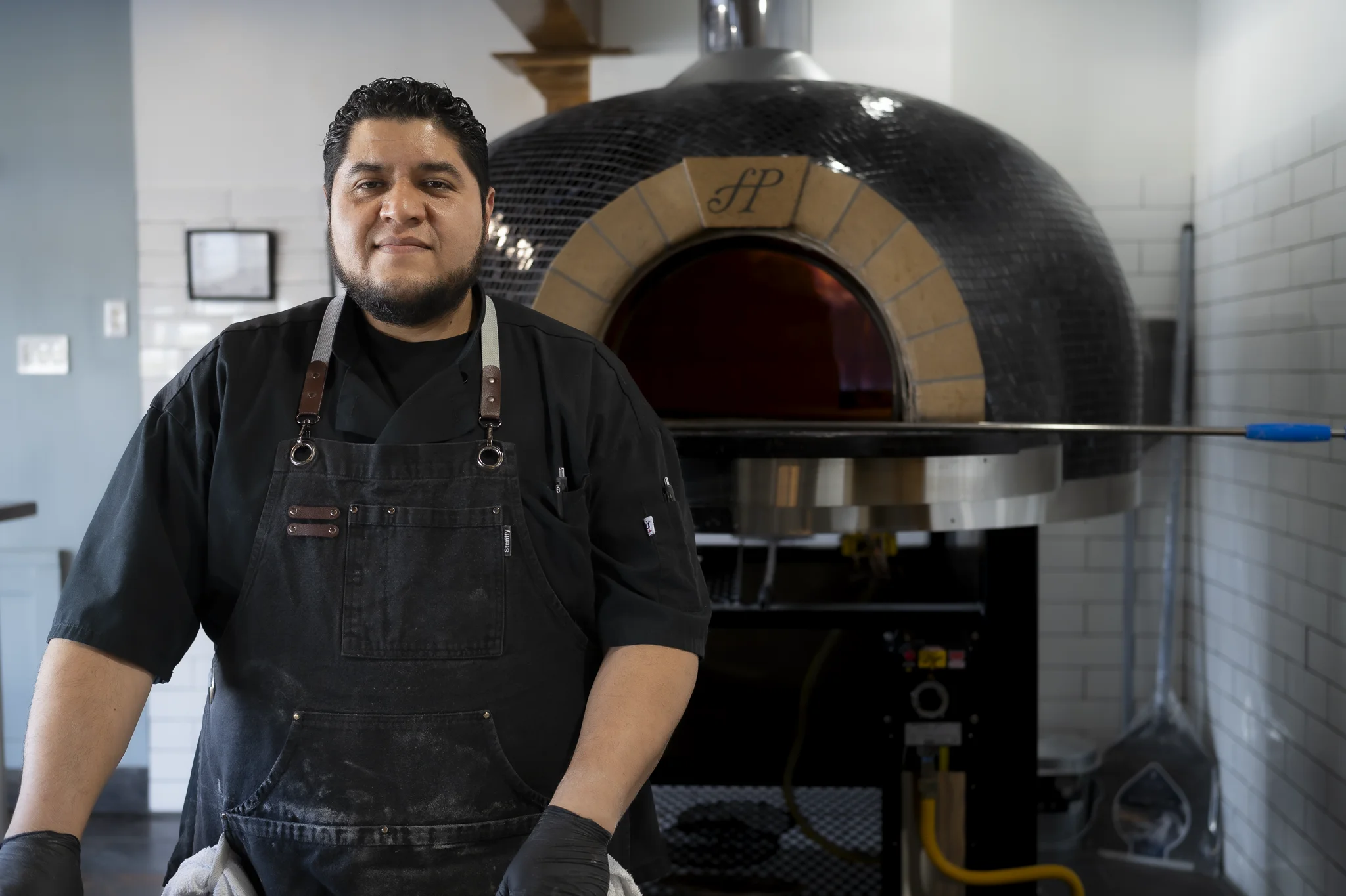 Chef Victor smiling in front of the El Fornino wood-fired pizza oven